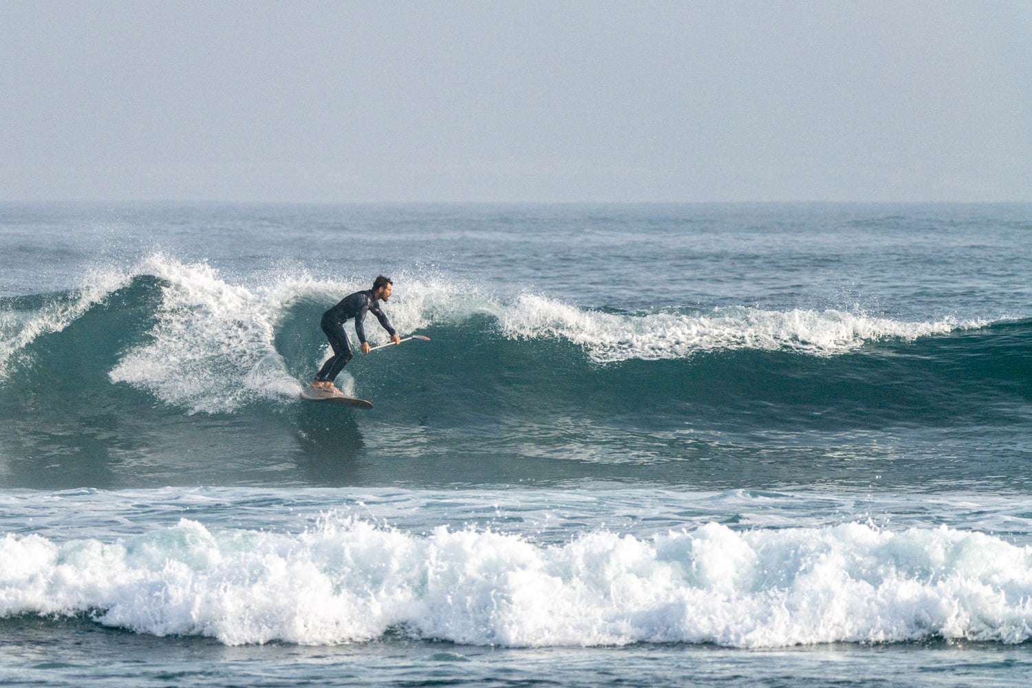 Stand up Paddler surft eine Welle mit einem Sunova Speeed Wave SUP Board.