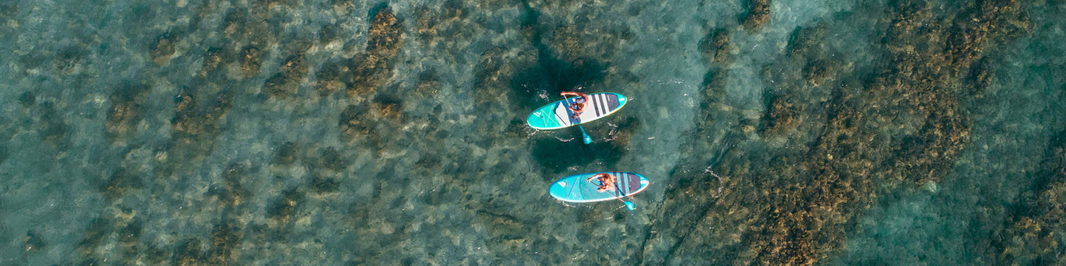 Drohnen Aufnahme von zwei Stand up Paddlern mit Fanatic iSUPs über einem tropischen Riff.