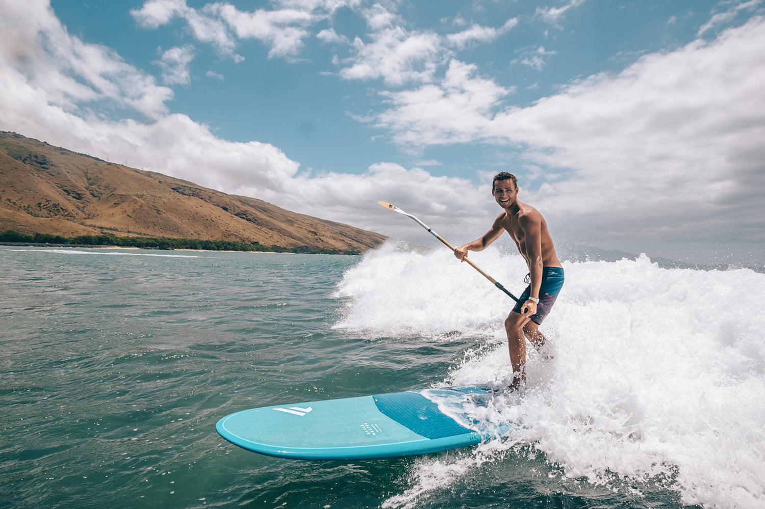Stand up Paddler mit Fanatic Stylemaster SUP Brett surft vor dem Weißwasser in einer Welle.