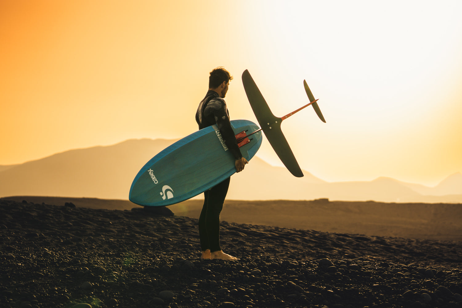 Prone Foiler Kai-Nicolas Steimer am Strand im Sonnenuntergang mit dem Sunova Casey Pilot Surf Foil Board und einem Axis Foil Set up.