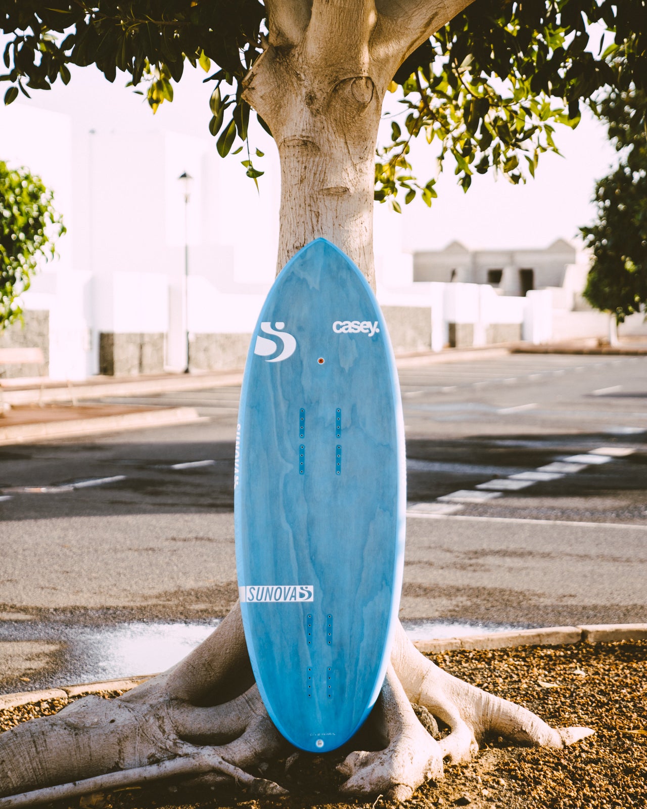 Sunova Casey Pilot Surf Pronefoil Board an einen Baum angelehnt.