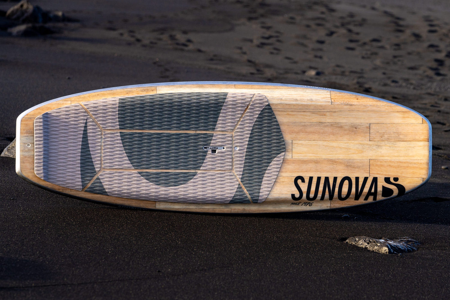 Sunova Shroom SUP Wave Board auf schwarzem Strand.