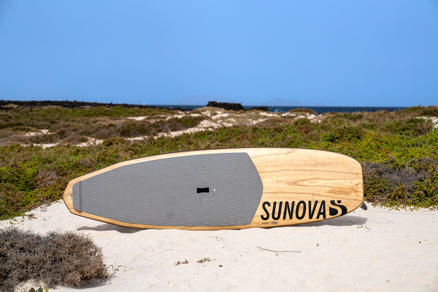 SUP Wave Board Sunova Speeed horizontal auf dem Rail am Strand.